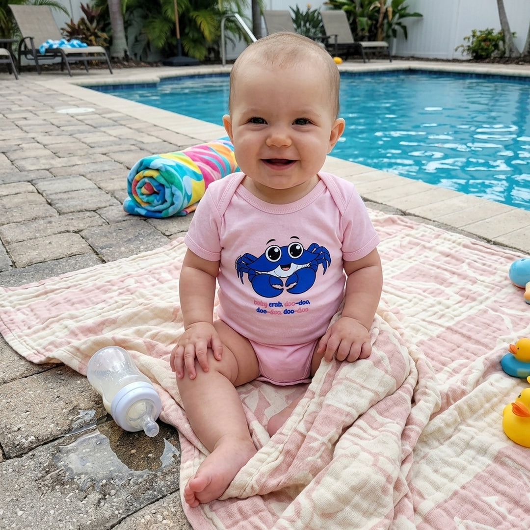 Pink baby crab onesie with the words baby crab doo-doo, doo-doo, doo-doo written under crab design. On a baby model.