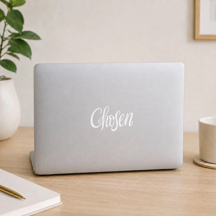 A light gray laptop with the vinyl sticker of the word &