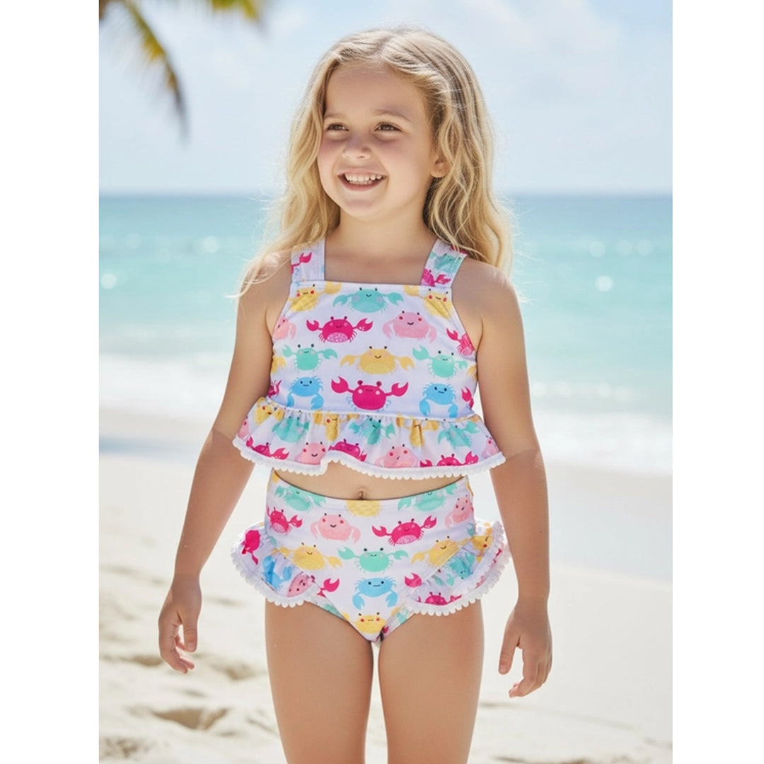 Young girl in a colorful crab-themed swimsuit on a beach