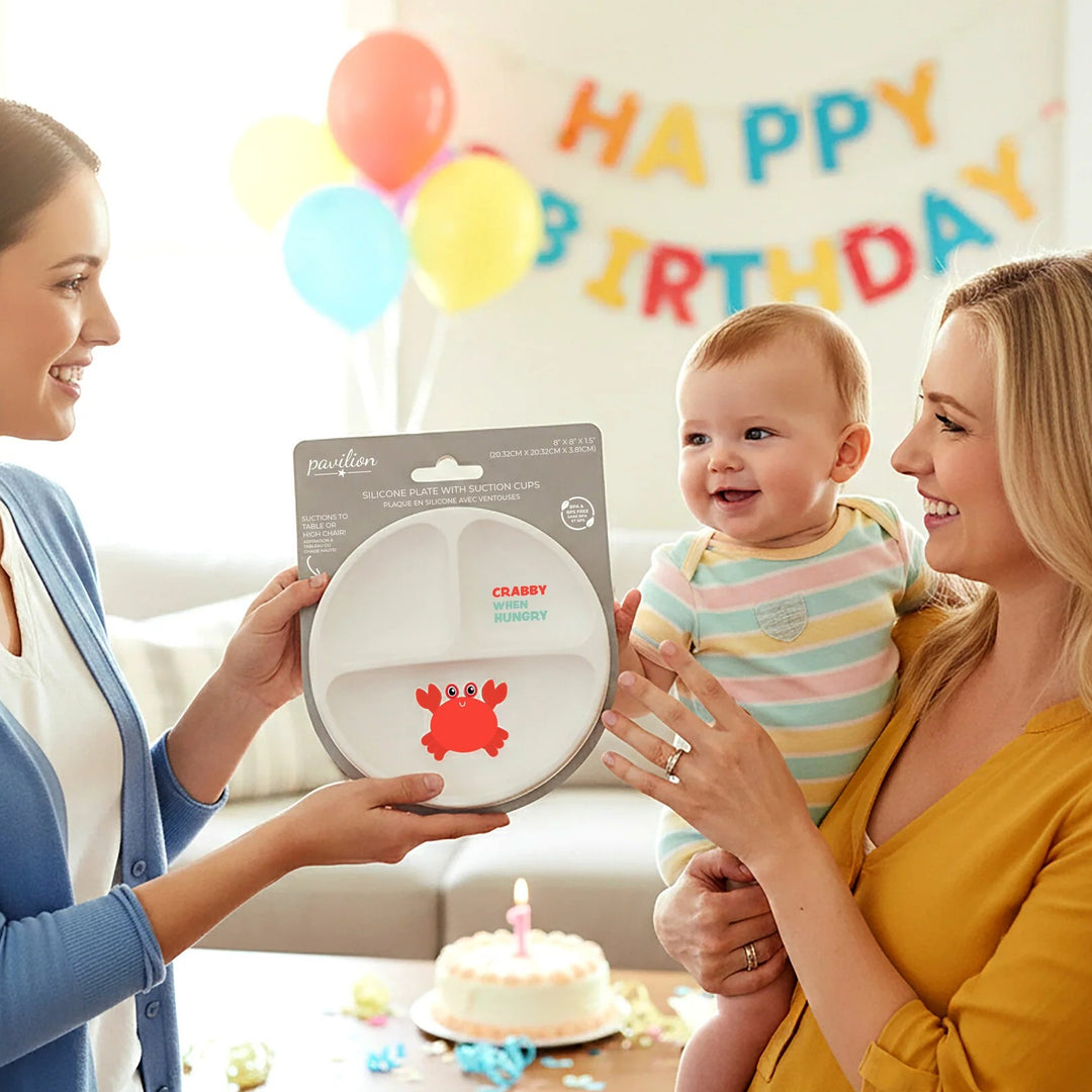 Woman holding a baby and a plate with colorful balloons and &