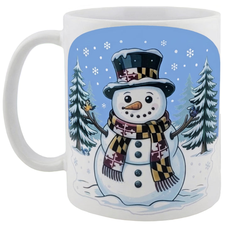 Maryland snowman coffee mug - a snowman with a Maryland flag scarf and hat with an oriole and a raven perched on the wood branch arms with pine trees in the background all on a white coffee mug