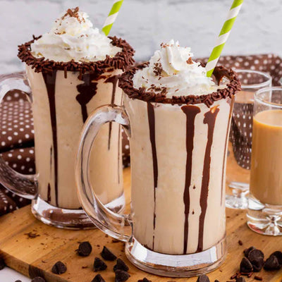 Two glasses of Noble Mick's Mudslide frozen cocktails with whipped cream and chocolate drizzle