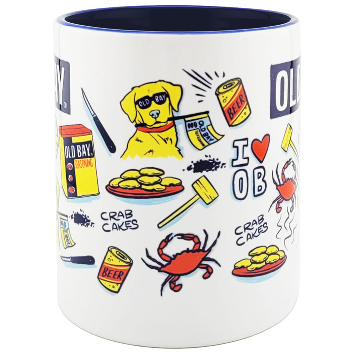 A white ceramic coffee mug with a dark navy blue interior and rim, decorated with colorful cartoon illustrations of an Old Bay dog, crab cakes, a red crab, beer cans, a crab mallet, and the text &