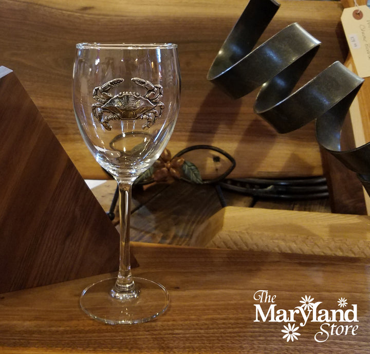 Clear glass wine glass with crab design on a wooden surface, branded &