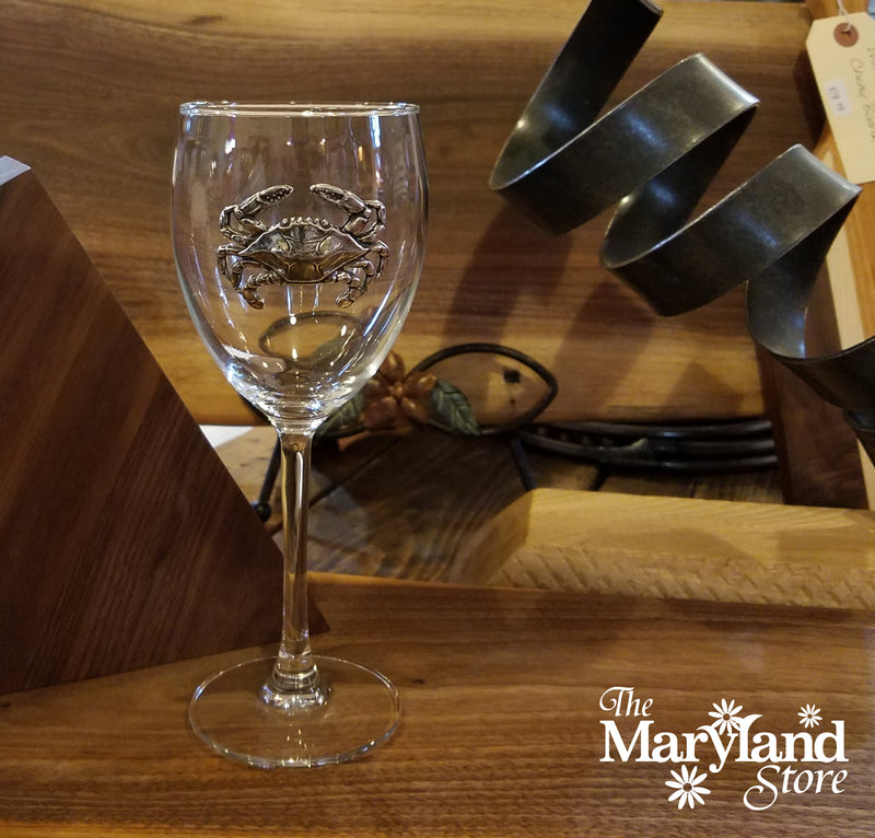 Clear glass wine glass with crab design on a wooden surface, branded &