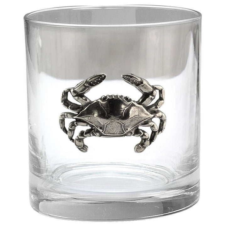 A clear glass rocks tumbler (old fashioned) featuring a detailed pewter crab medallion in the center.