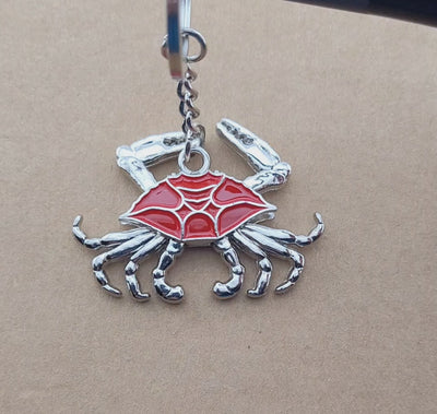 video of key ring with a blue shell crab and moveable chrome look legs