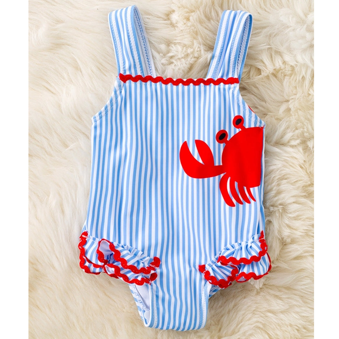 Blue and white striped baby romper with red crab design on a fluffy beige surface