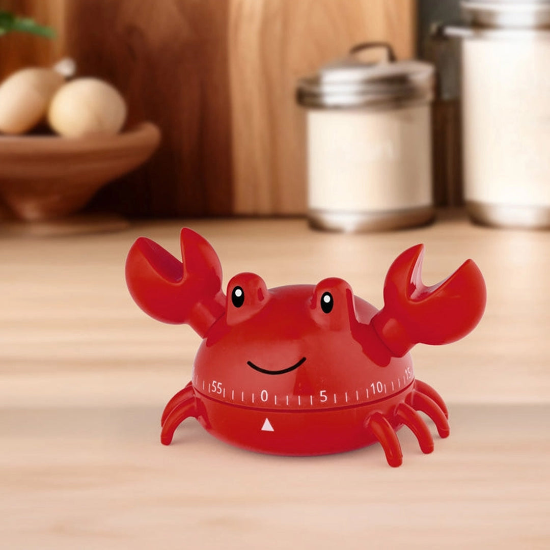 Red crab-shaped kitchen timer on a wooden surface with jars in the background