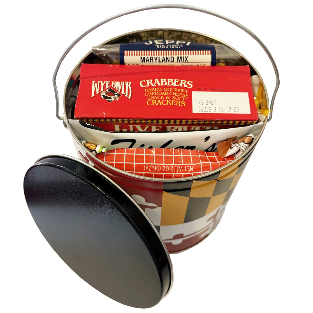 A novelty metal tin filled with assorted packaged snacks and crackers, shown on a white background with the black lid leaning against the front left side.