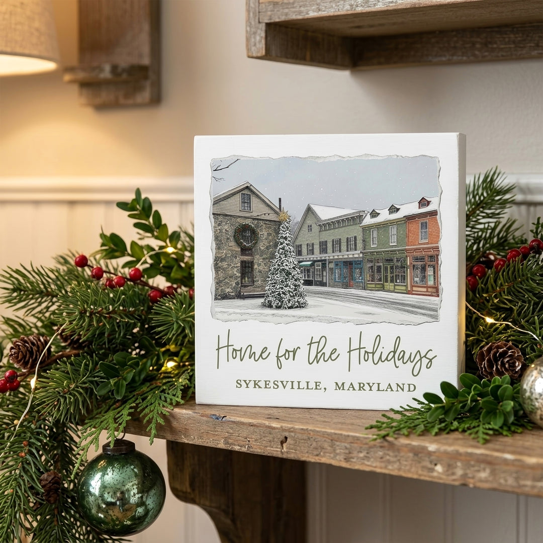 Sykesville Maryland Home For The Holidays 5" Box Sign on a mantle decorated for Christmas.