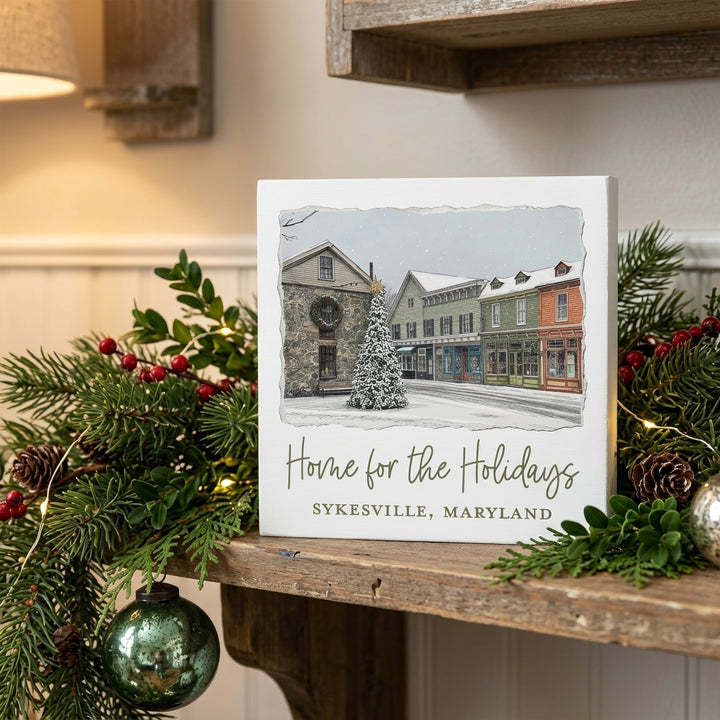 Sykesville Maryland Home For The Holidays 5" Box Sign on a mantle decorated for Christmas.