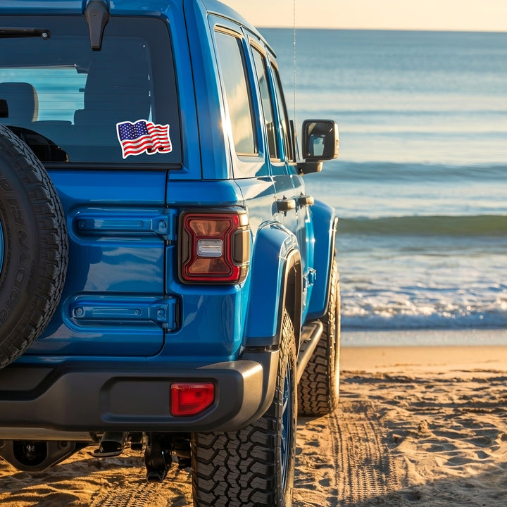 Waving American Flag Die Cut Vinyl Sticker on a blue vehicle back window.